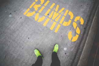 person standing next to the word bumps painted in yellow on a road